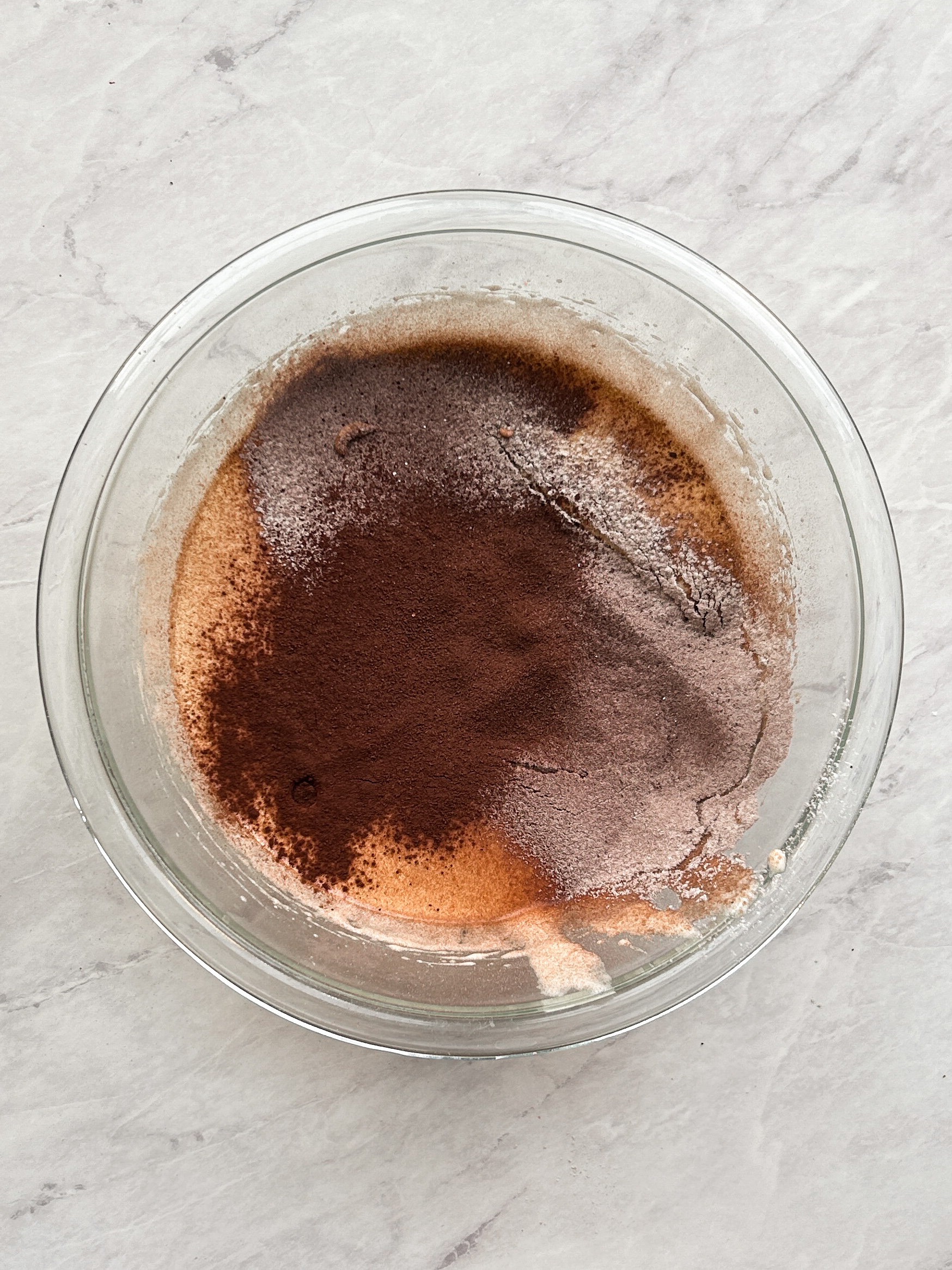 flour and cocoa powder added to eggs and sugar in a glass bowl