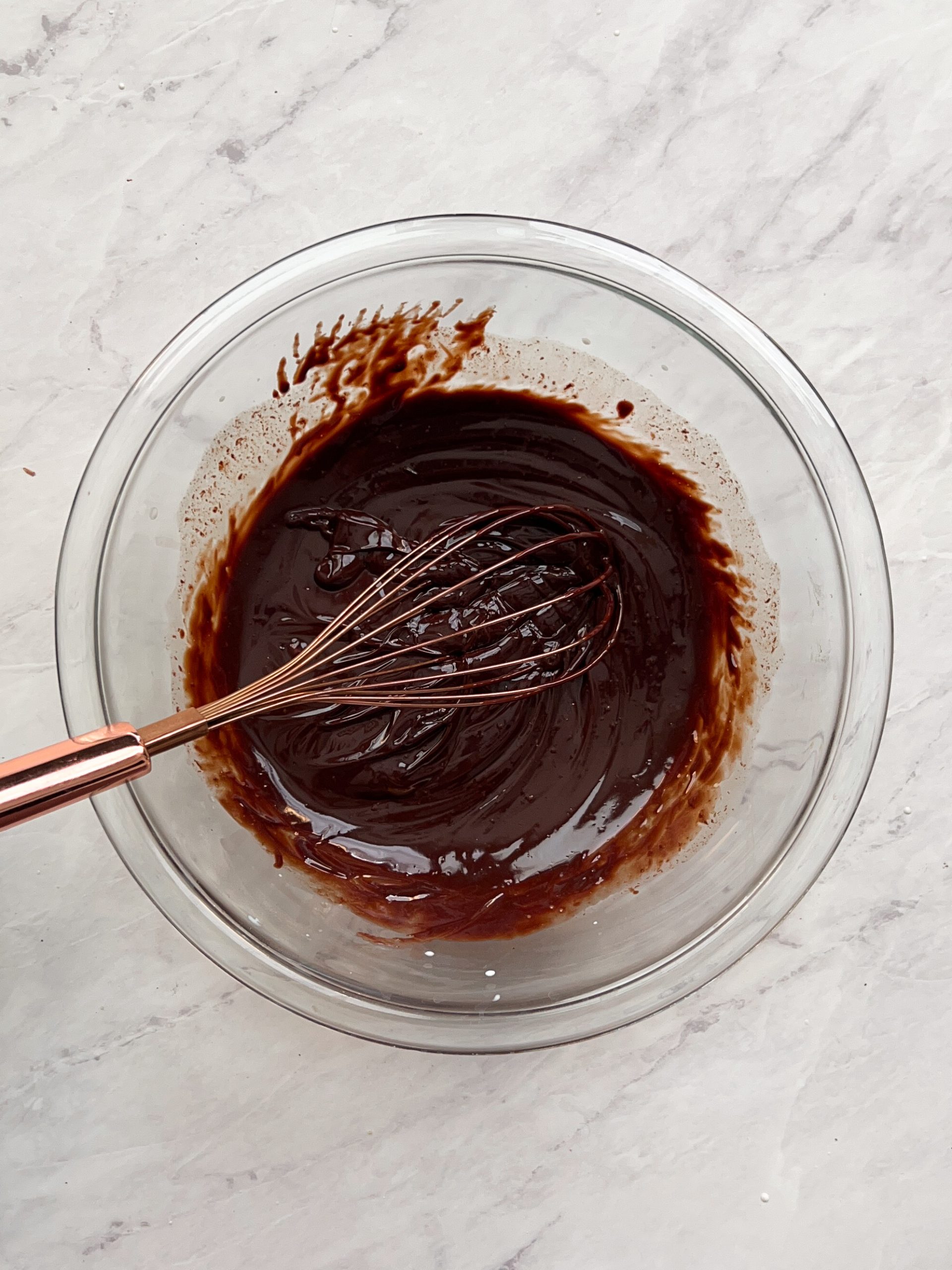 chocolate ganache in a glass bowl, with a whisk inside