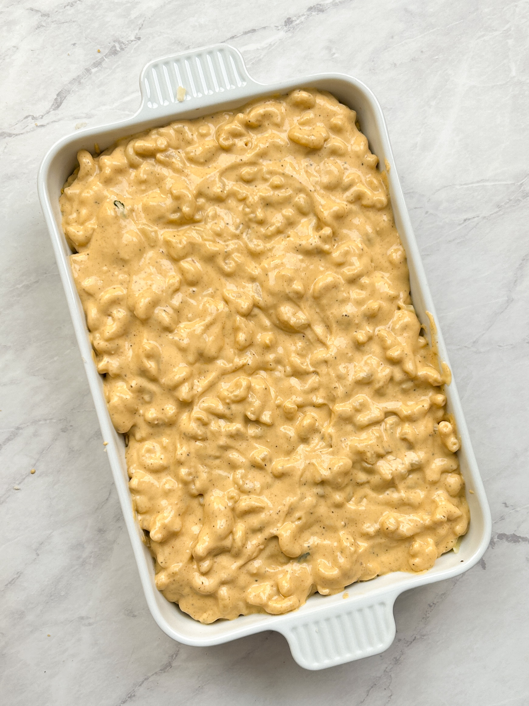mac and cheese layered in a white casserole dish