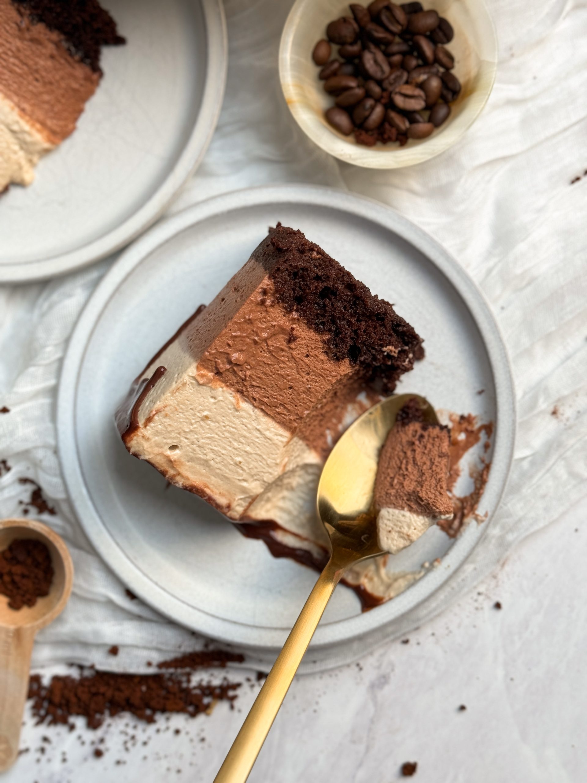a slice of mocha mousse cake on a small plate with a spoon pulling out a bite. picture from the top