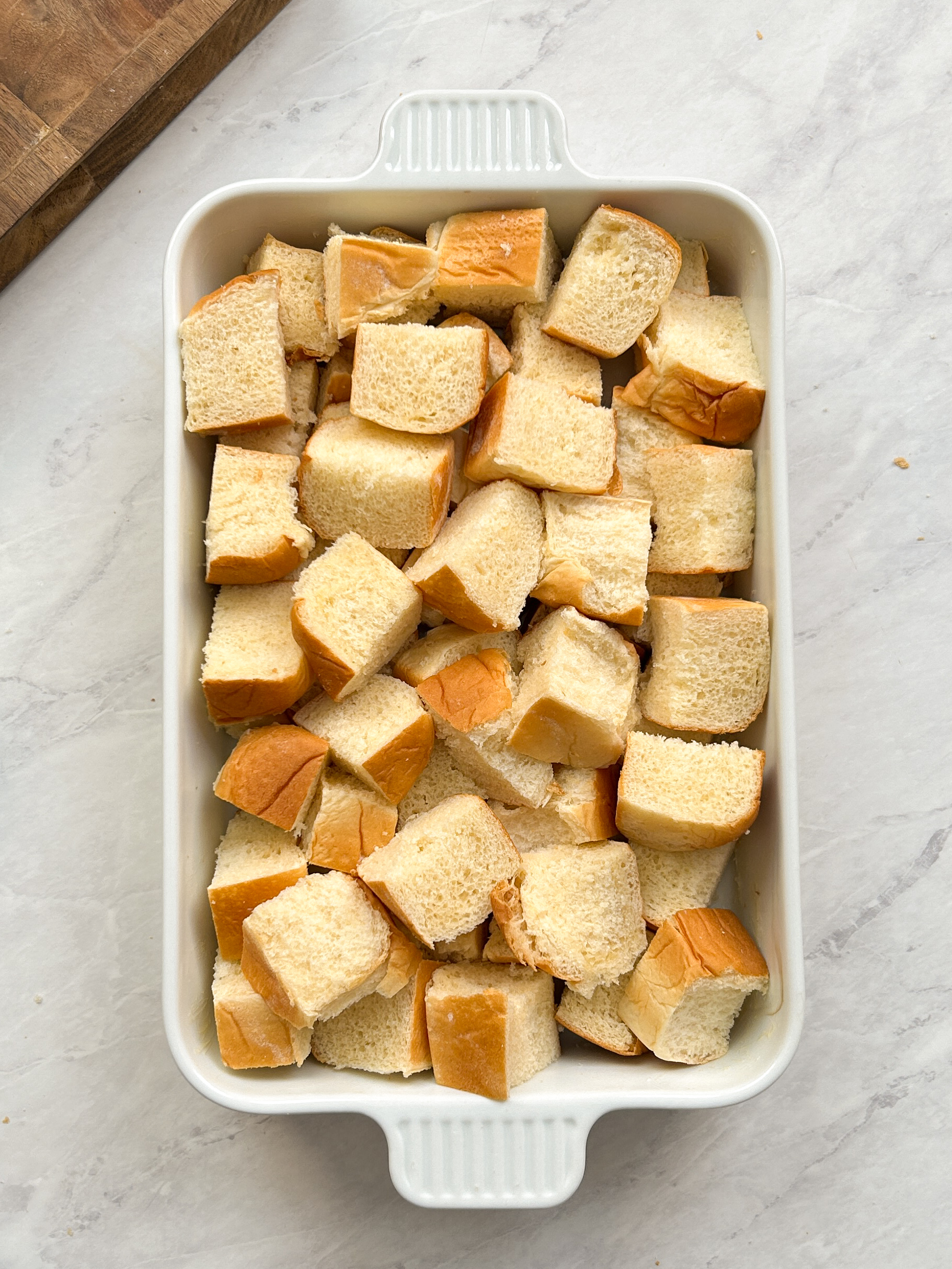 large cubes of bread in a white rectangular baking dish arranged haphazardly