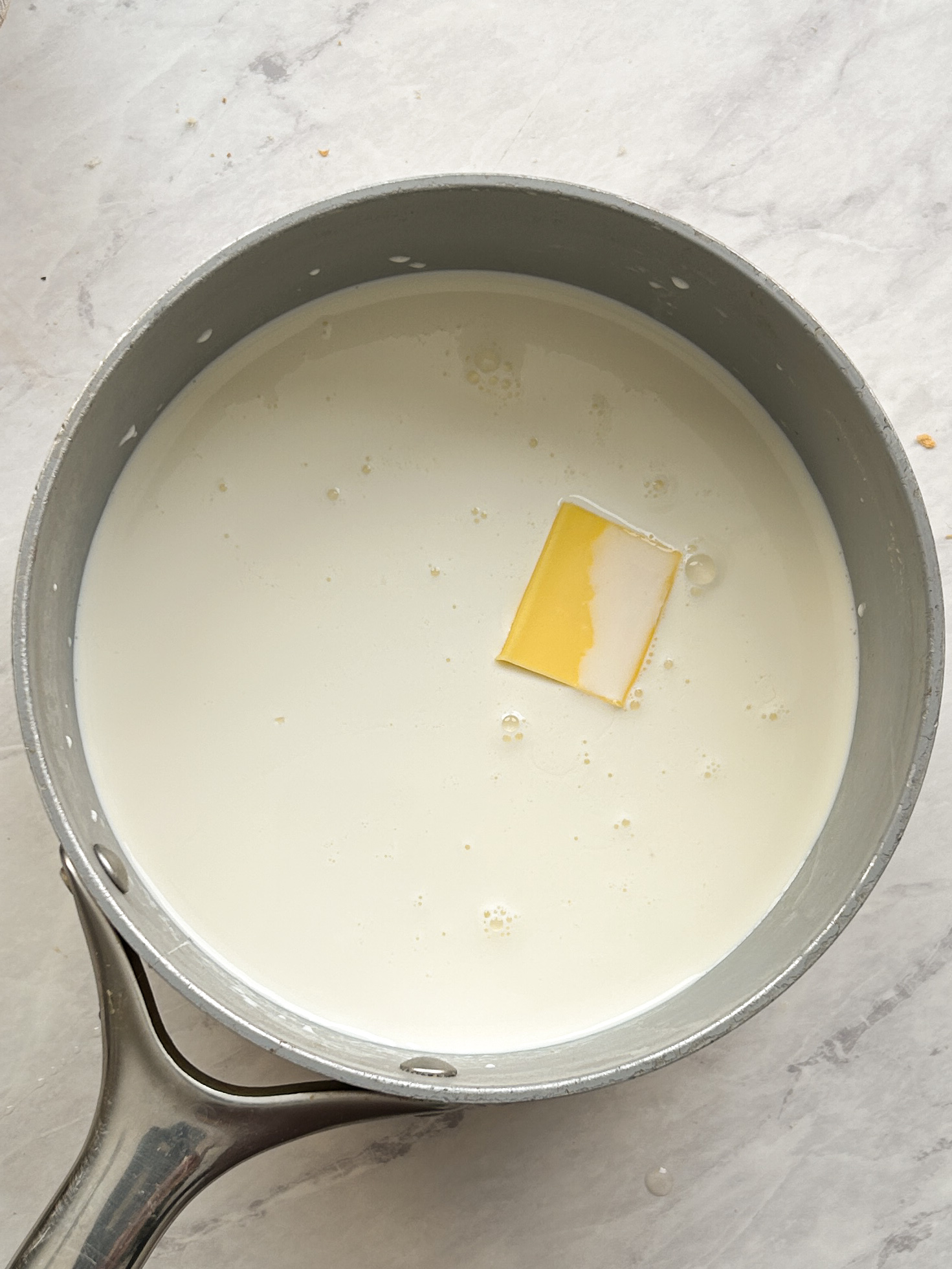 vanilla custard ingredients in a saucepan, a cube of butter seen inside
