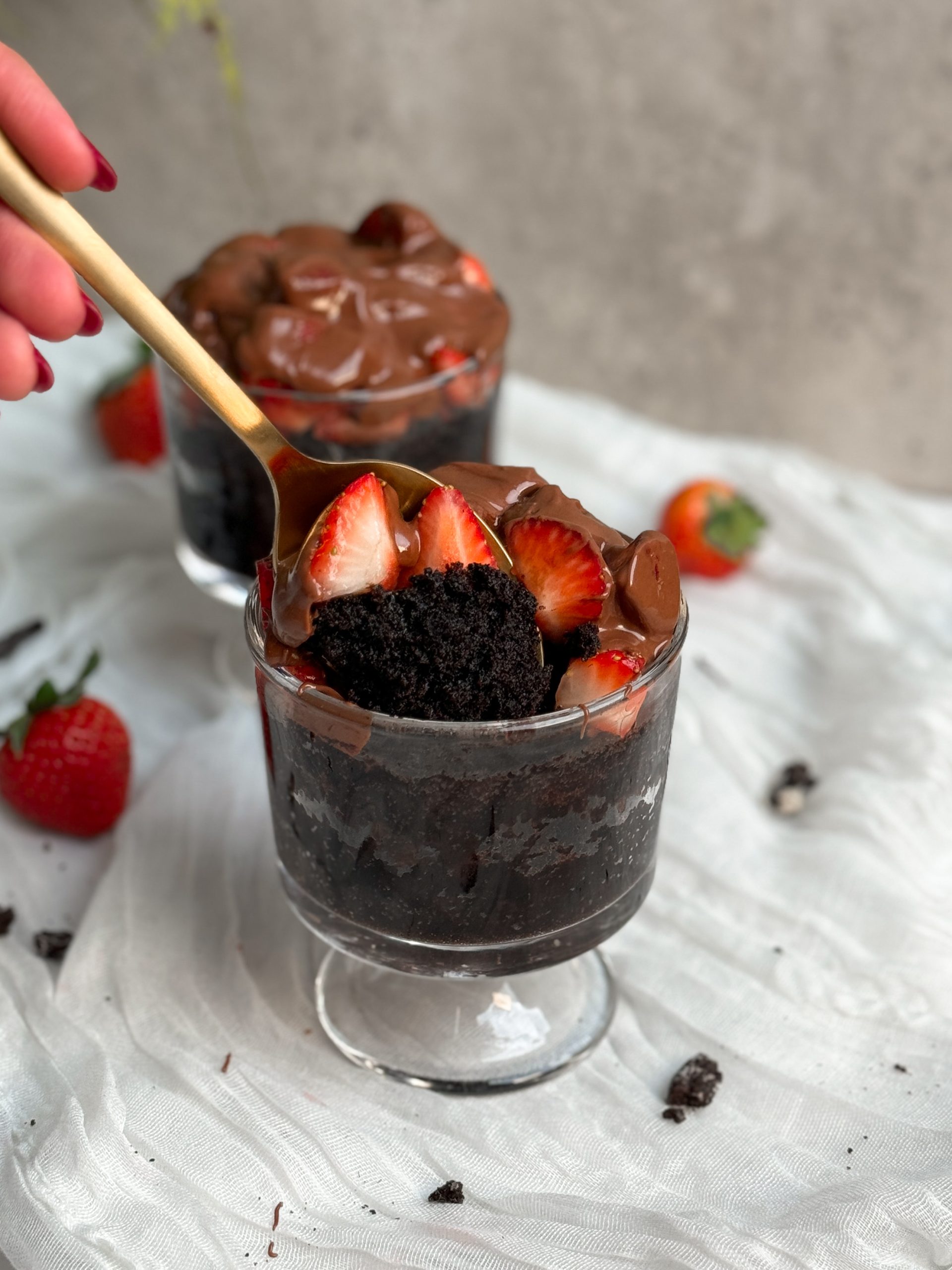 chocolate strawberry mug cake with a spoon pulling out a bite showing the moist rich texture inside