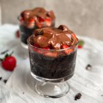 2 glass cups with chocolate strawberry mug cakes inside. moist chocolate cake topped with chopped strawberries and melted chocolate