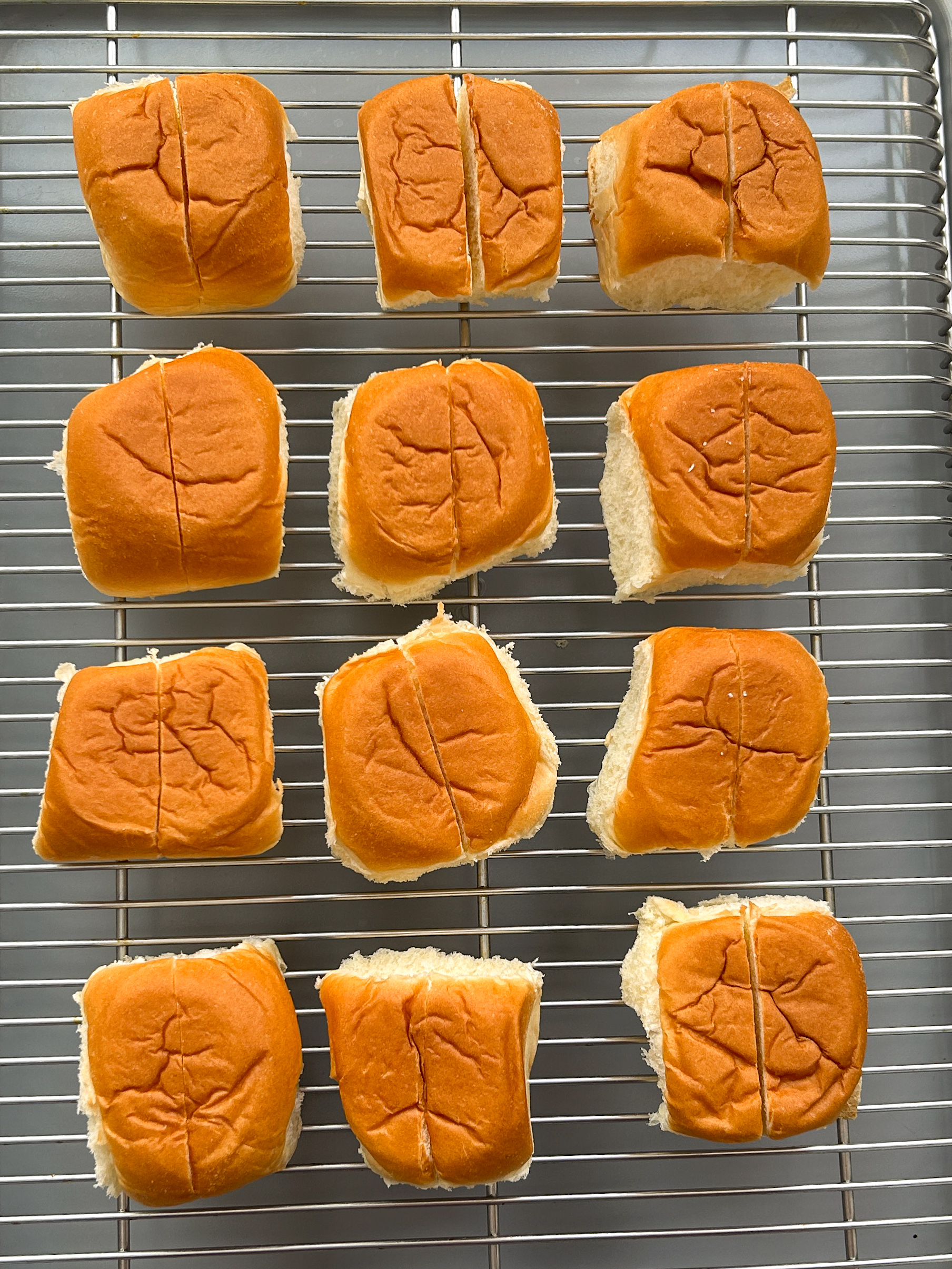 12 buns with a cut down the middle on a wire rack
