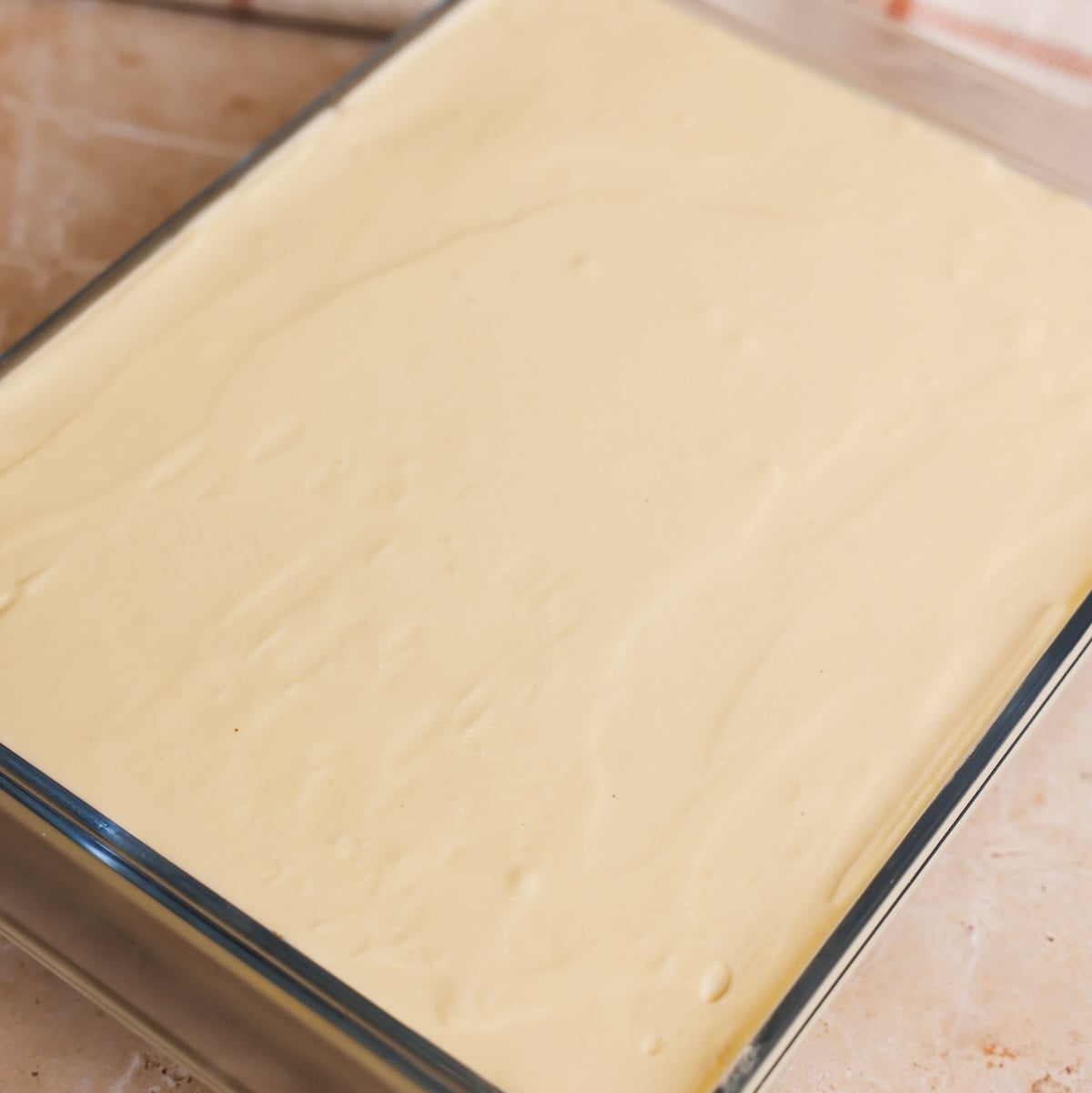 A glass baking dish filled with a smooth, creamy, pale yellow mascarpone mixture