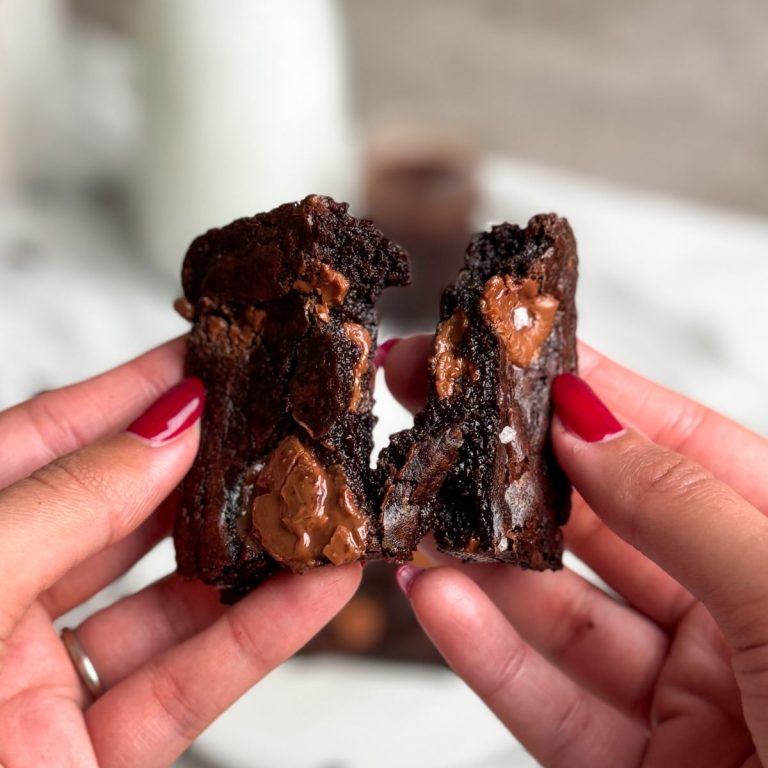 hand holding a single serve brownie and pulling it into 2 halves showing the gooey and fudgy texture inside