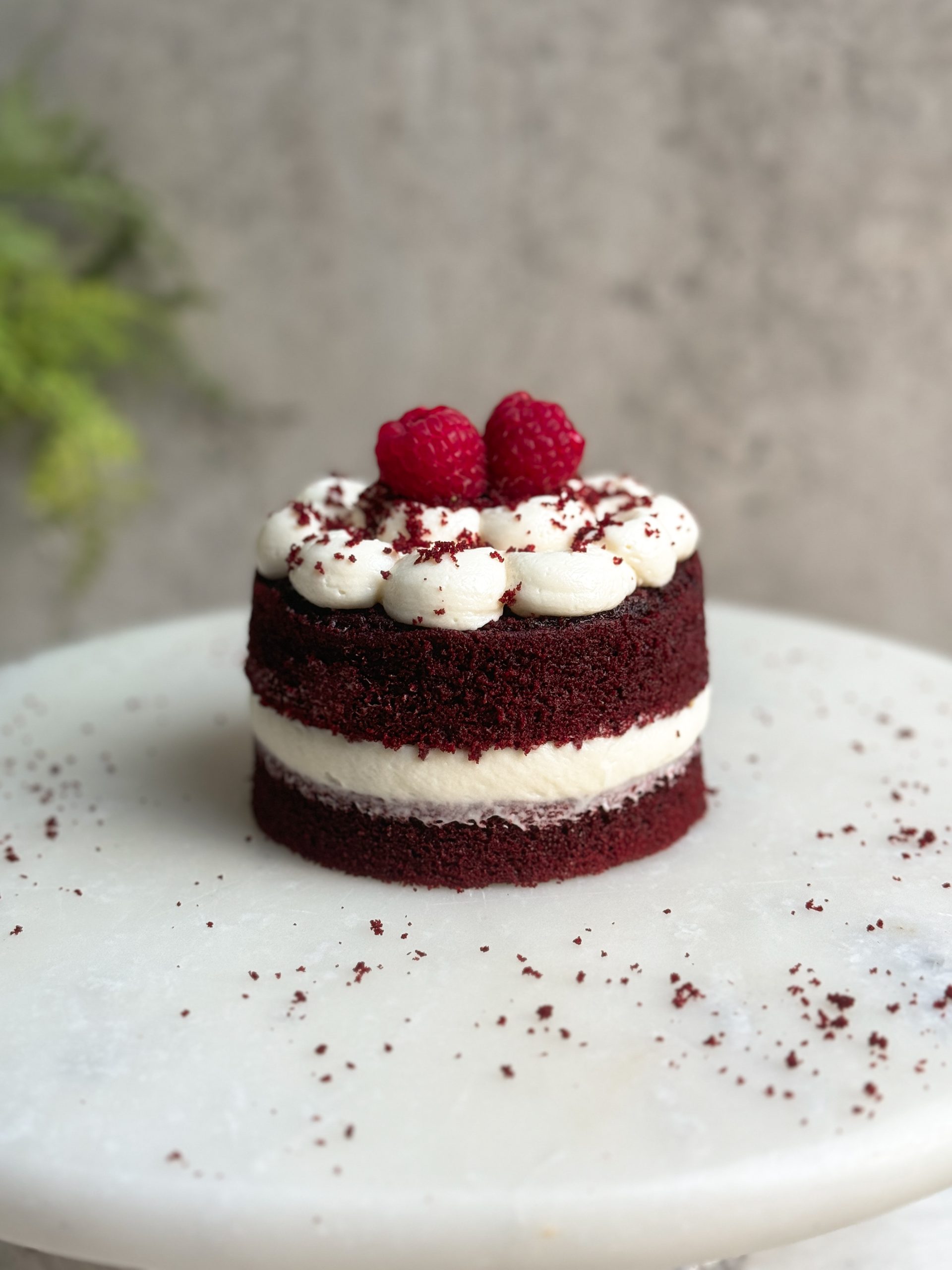 single serve small red velvet cake with cream cheese frosting on a marble serving board