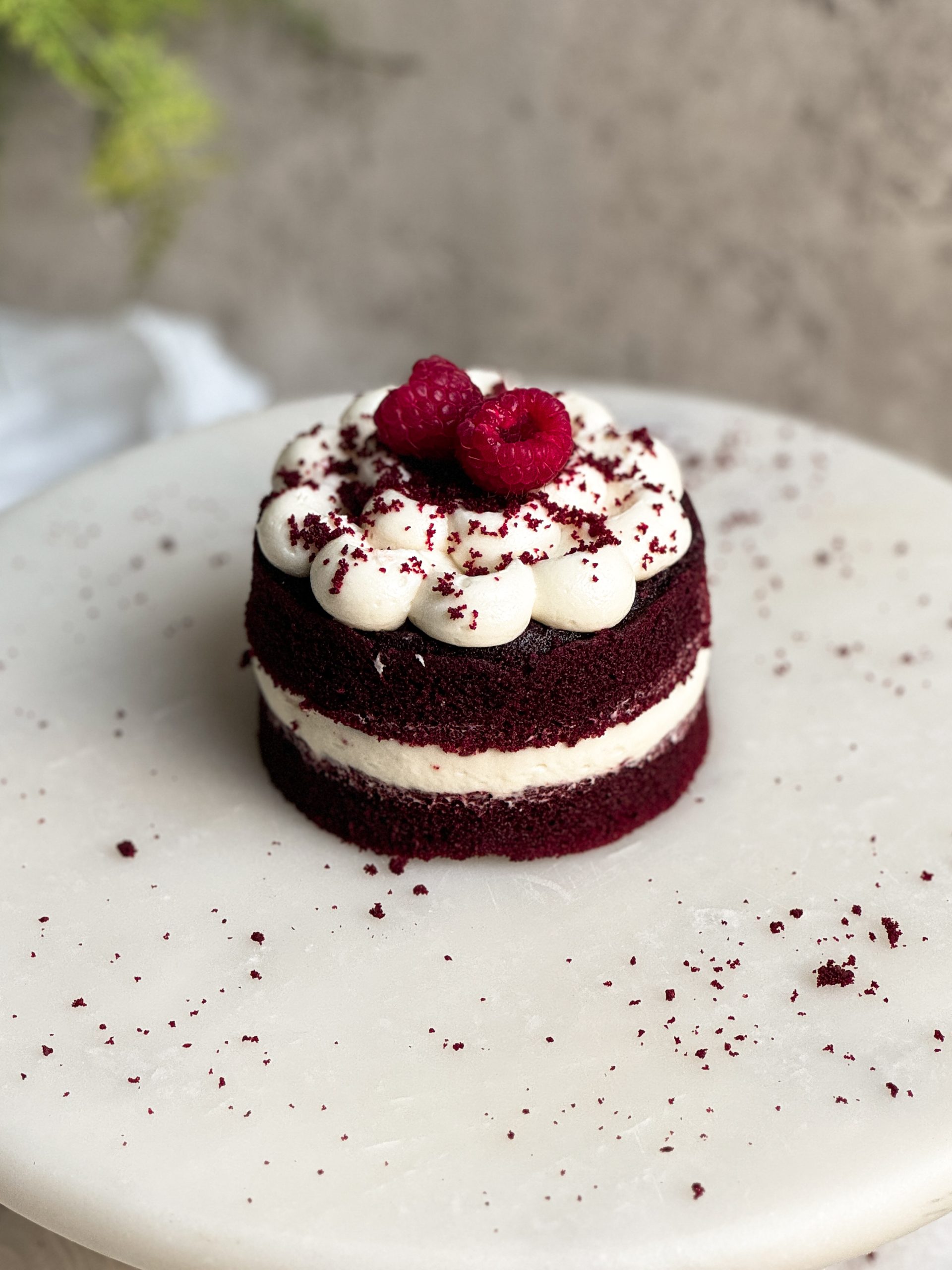 single serve small red velvet cake with cream cheese frosting on a marble serving board. picture from an angle