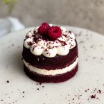 single serve small red velvet cake with cream cheese frosting on a marble serving board. picture from an angle