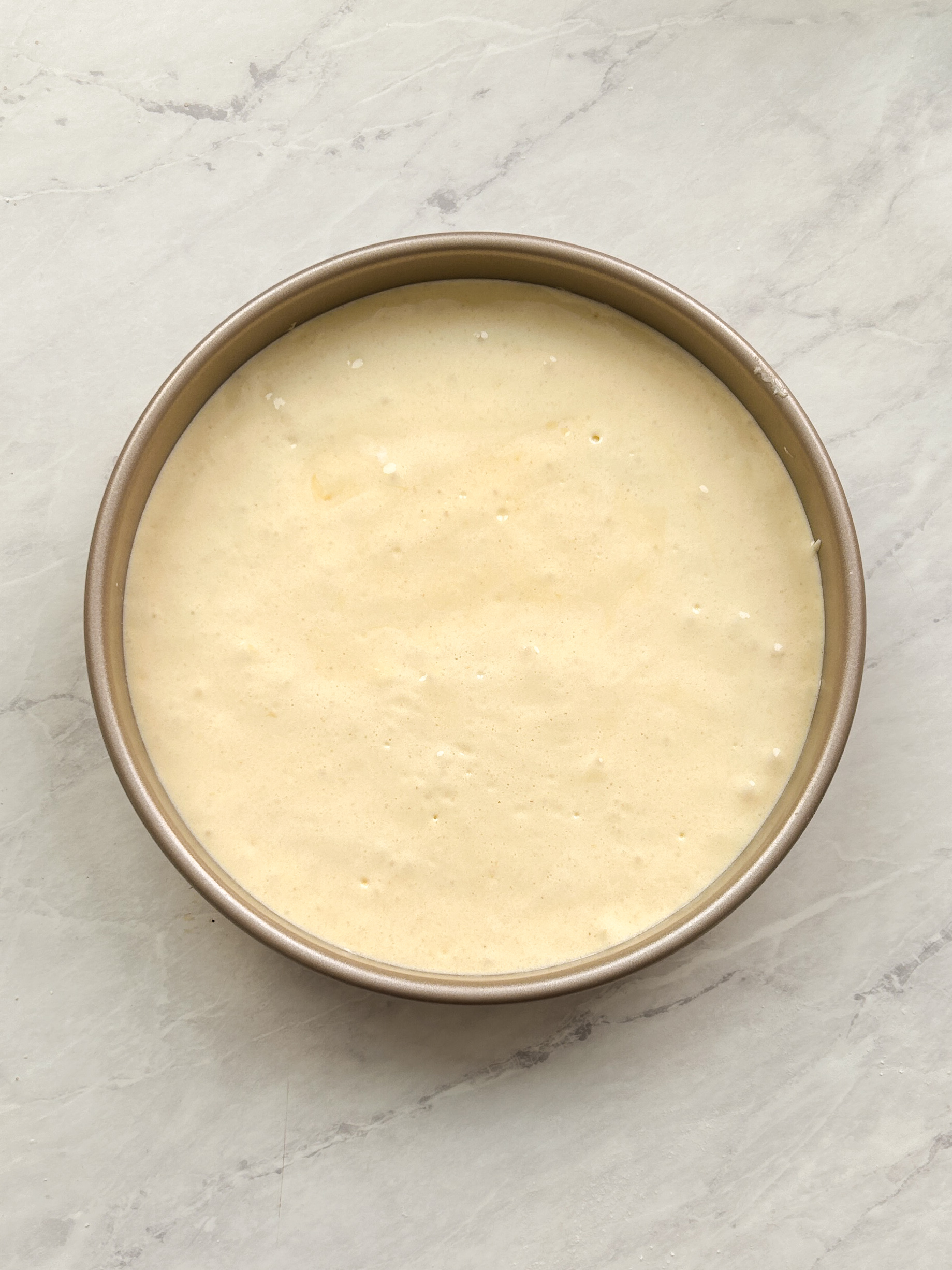 tres leches cake batter in a round baking tin