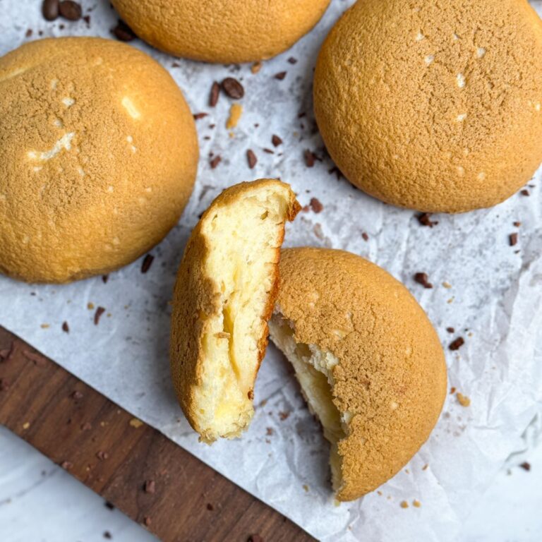 papparoti coffee buns with a golden crispy crust on top. one bun is split in half and placed sideways to show the soft buttery interior