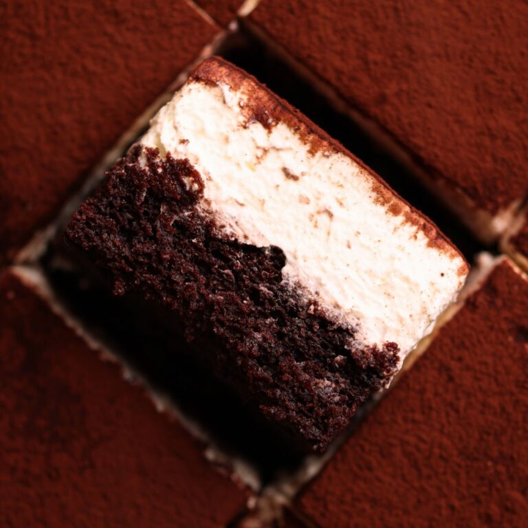 slice of tiramisu chocolate cake placed sideways to show the layers of moist chocolate cake and mascarpone cream, surrounded by more slices on the side