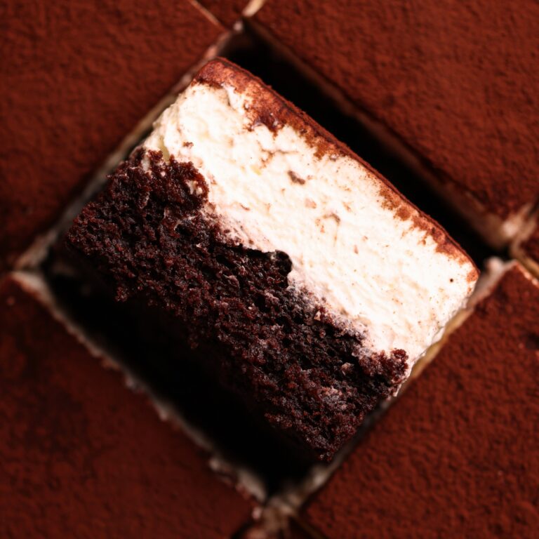 slice of tiramisu chocolate cake placed sideways to show the layers of moist chocolate cake and mascarpone cream, surrounded by more slices on the side