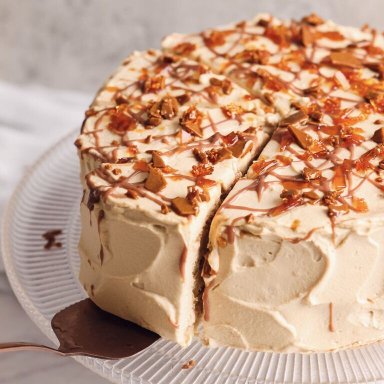 caramel cloud cake on a cake stand with a spatula pulling out a slice