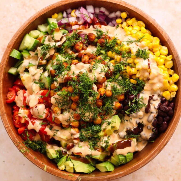 large wooden bowl with southwest bbq salad ingredients drizzled with the dressing and chopped dill
