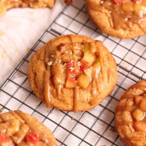 apple pie snickerdoodle cookie close up. cookie has an apple pie filling on top and is drizzled with a caramel sauce