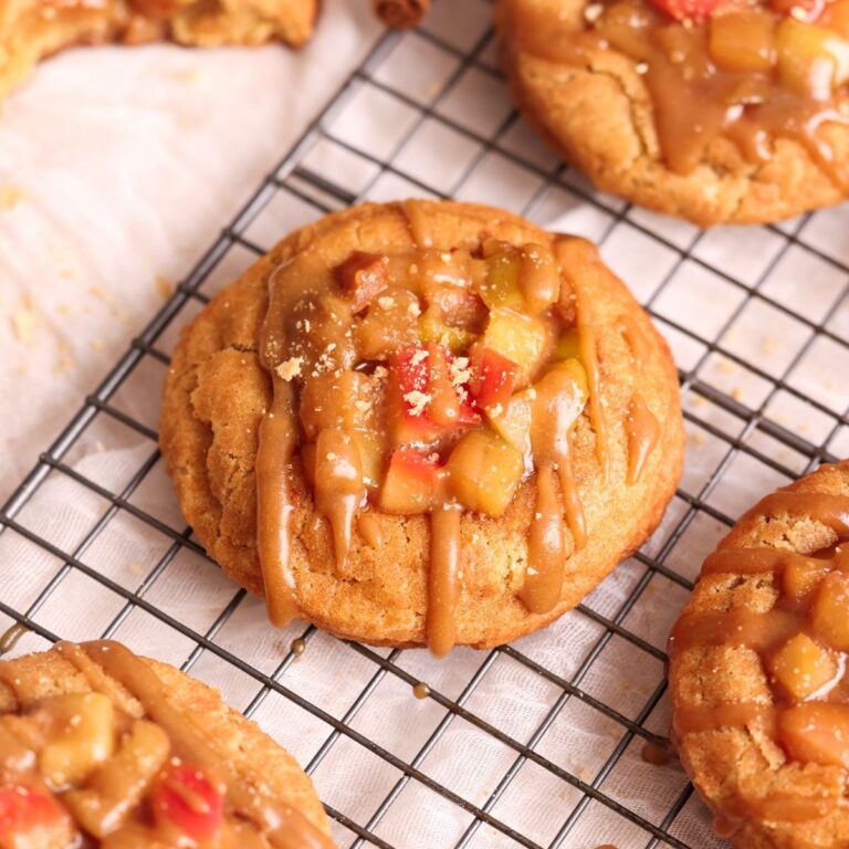 apple pie snickerdoodle cookie close up. cookie has an apple pie filling on top and is drizzled with a caramel sauce