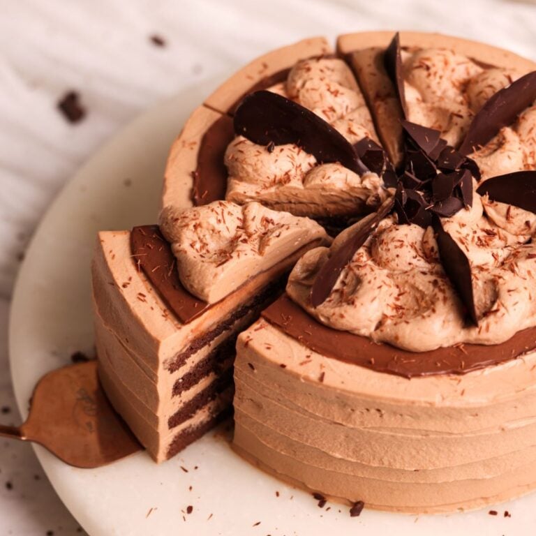 slice of chocolate mousse chiffon cake being pulled out from the cake, showing the decoration of mousse and ganache and the layers of chocolate chiffon cake and mousse cream