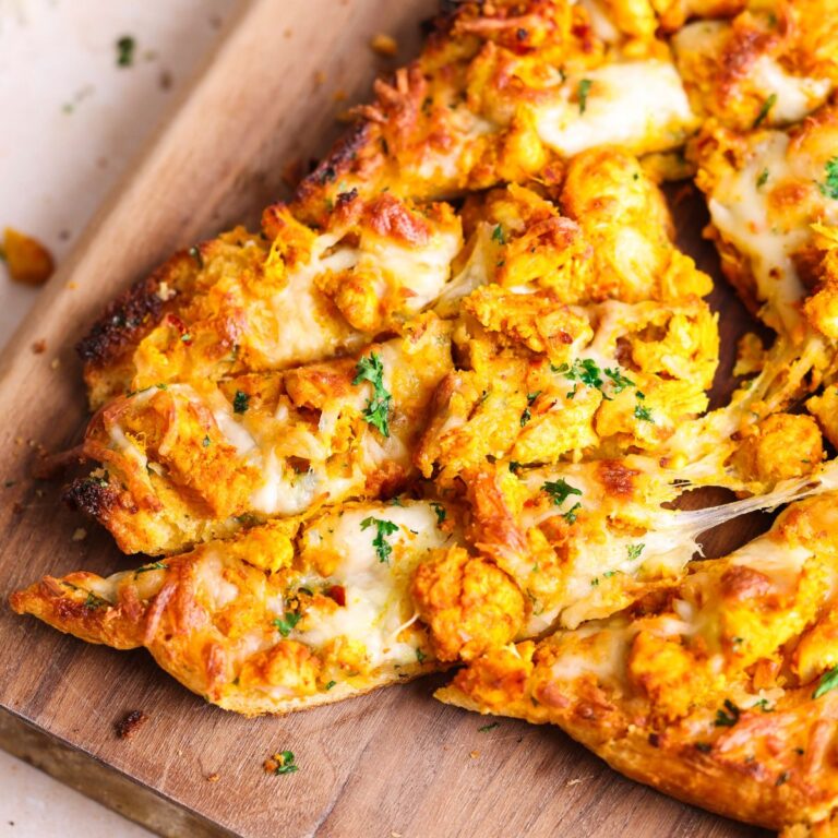 Close up of three tandoori chicken garlic bread sliders that are being pulled apart from the bread with a cheese pull