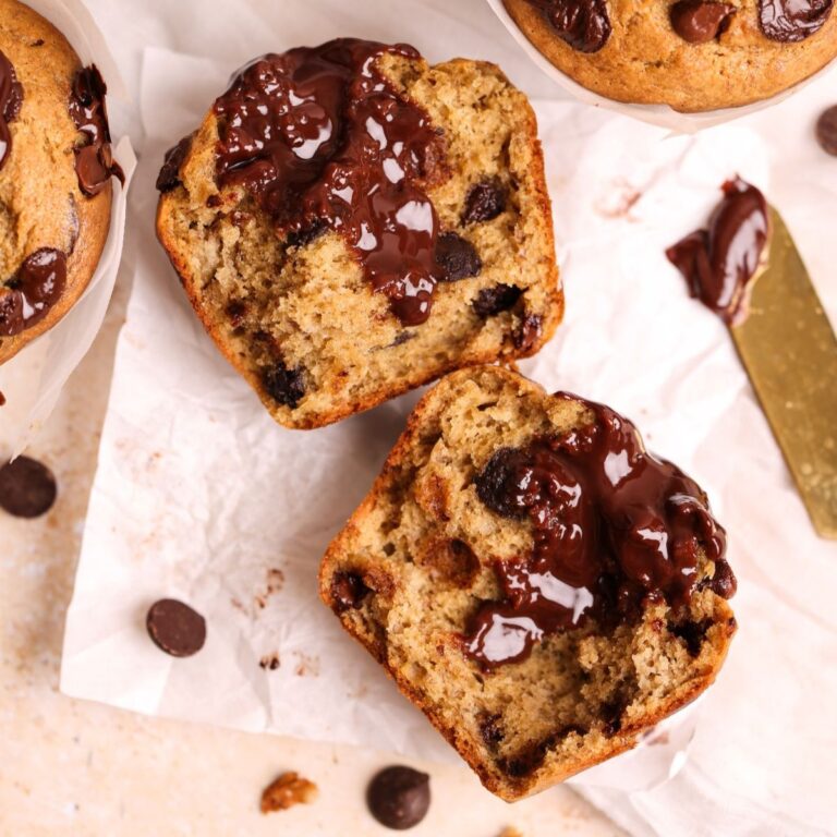 overhead image of banana chocolate muffins, with one muffin broken into 2 halves to show the moist and soft inside and chocolate ganache filling