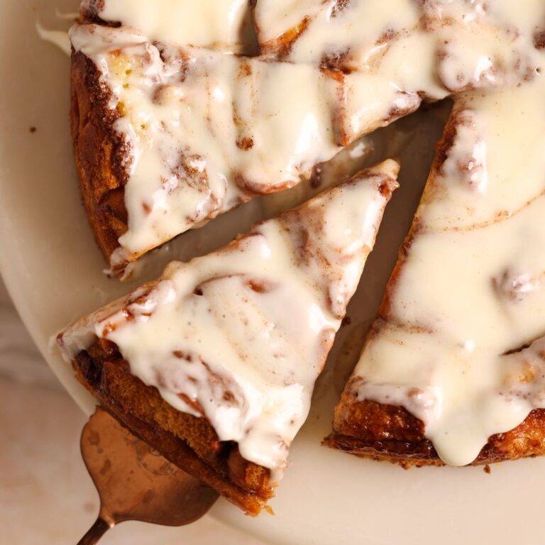 overhead picture of cinnamon roll bread pudding covered in cream cheese icing with a spatula pulling out one slice