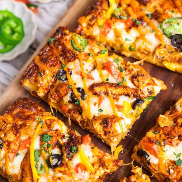close up of a slice of chipotle chicken pizza. pizza has a golden crispy crust and is topped with chicken veggies and cheese