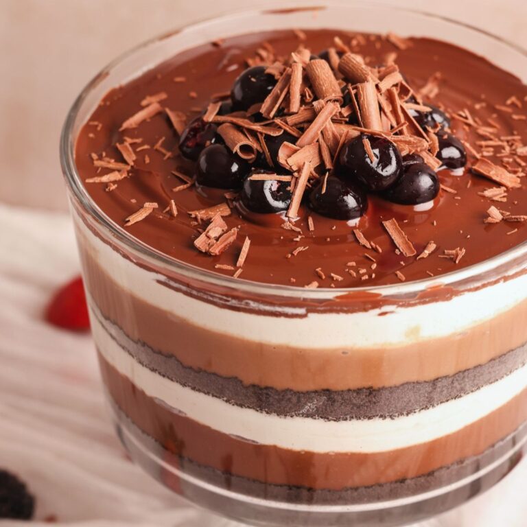 close up of chocolate lasagna trifle in a glass trifle bowl with layers of crushed cookies, chocolate pudding and whipped cream