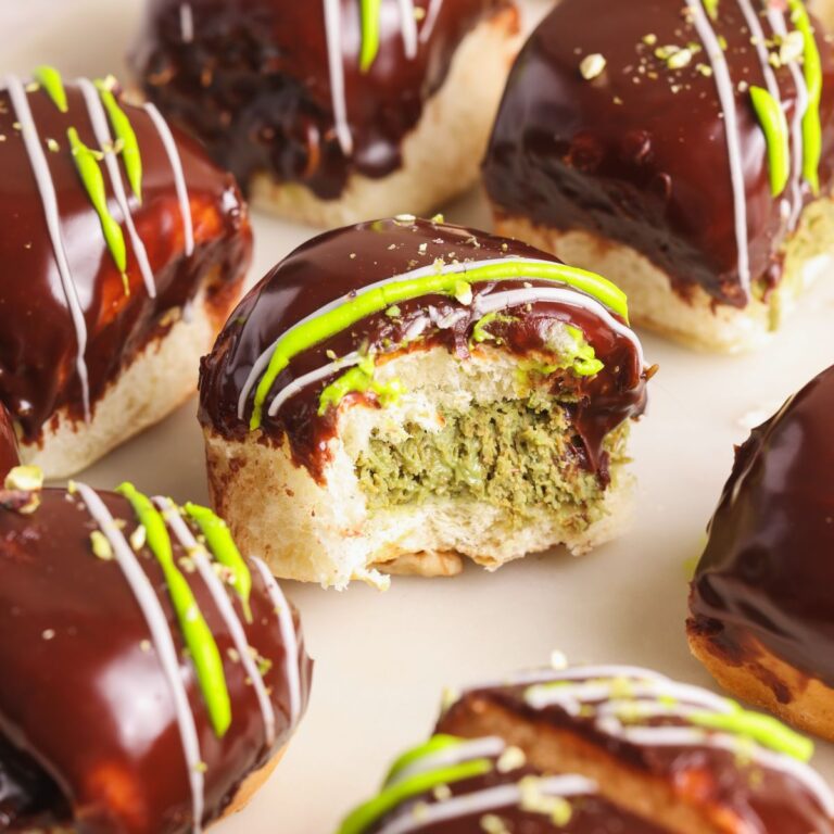 close up of dubai chocolate donut with a bite taken to show the crispy pistachio knafeh filling