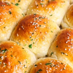 close up of a batch of paneer tikka naan buns with a shiny golden crust and sesame seeds