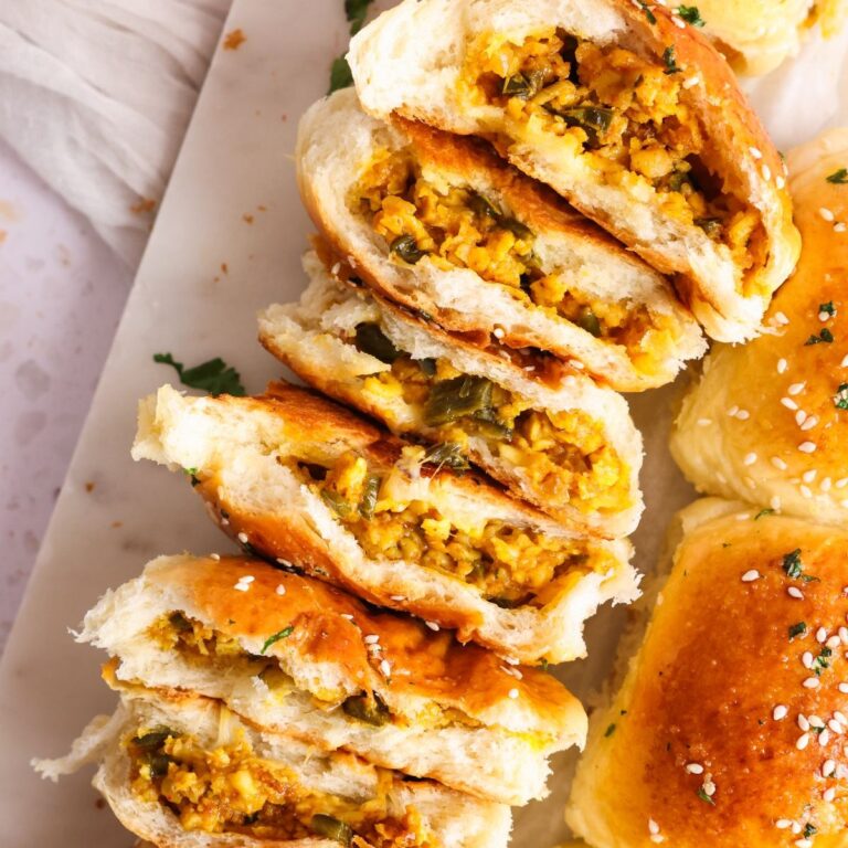 paneer tikka naan buns torn into halves to show the paneer tikka filling inside