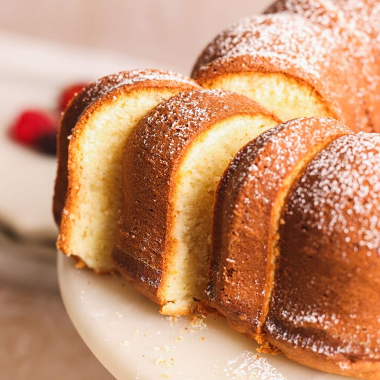 2 slices of pound cake being pulled out from it and pictured from the side. texture is soft and crust is golden and crispy