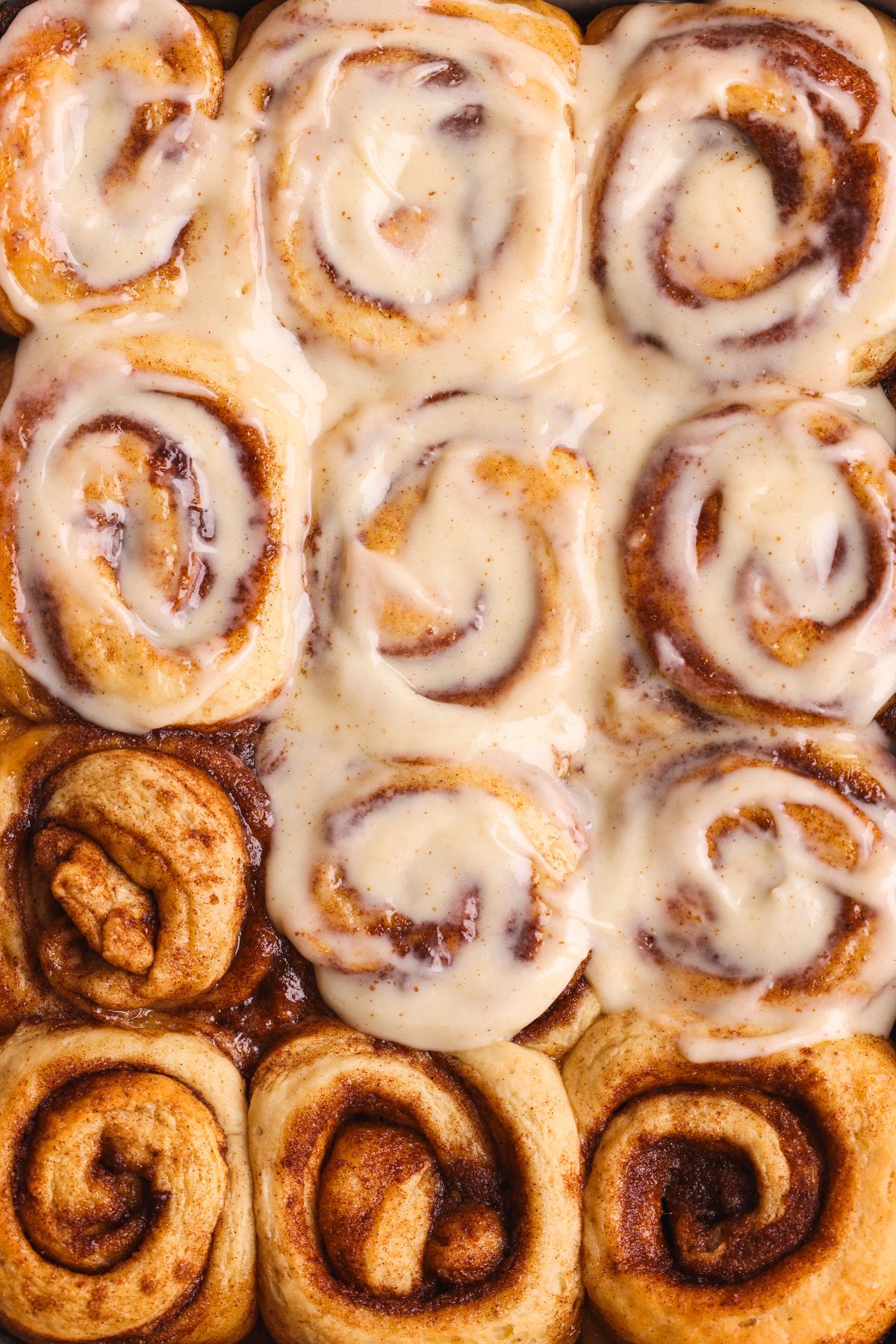 12 sticky banana bread cinnamon rolls, with cream cheese icing spread on top of 8 of them