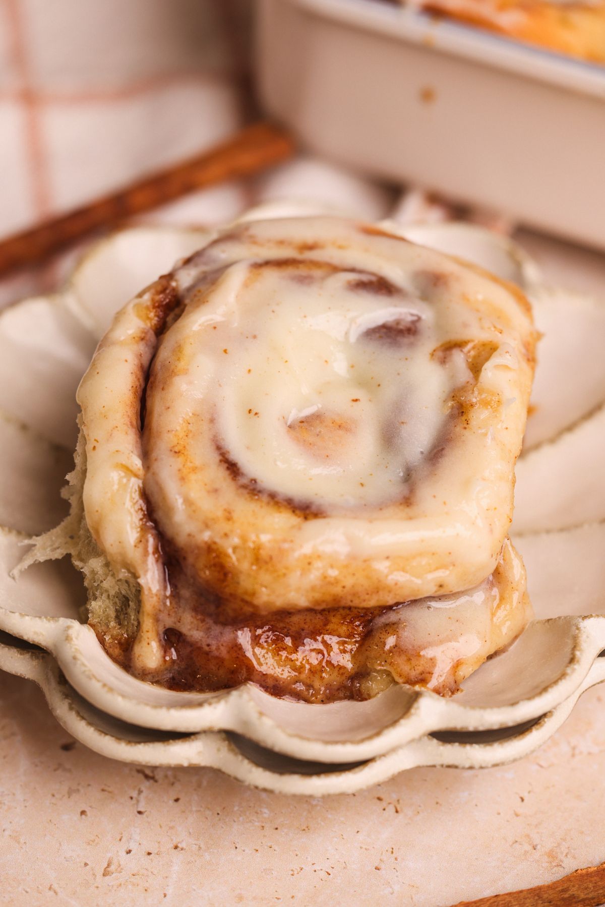 a banana bread cinnamon roll on a small plate with cream cheese icing on top