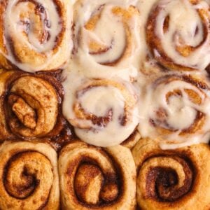 9 sticky banana bread cinnamon rolls with cream cheese icing spread on 5 of them