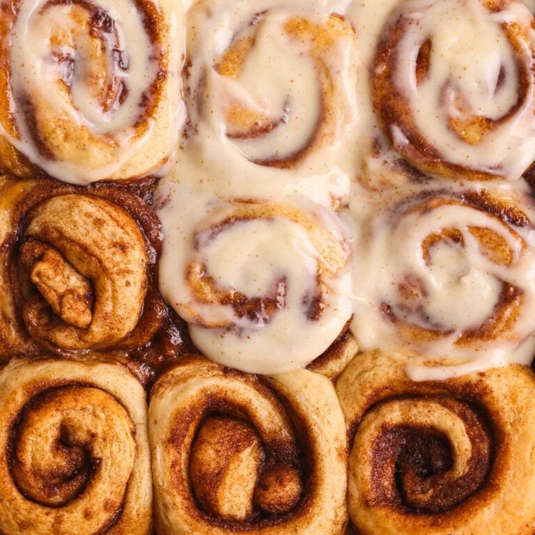 9 sticky banana bread cinnamon rolls with cream cheese icing spread on 5 of them