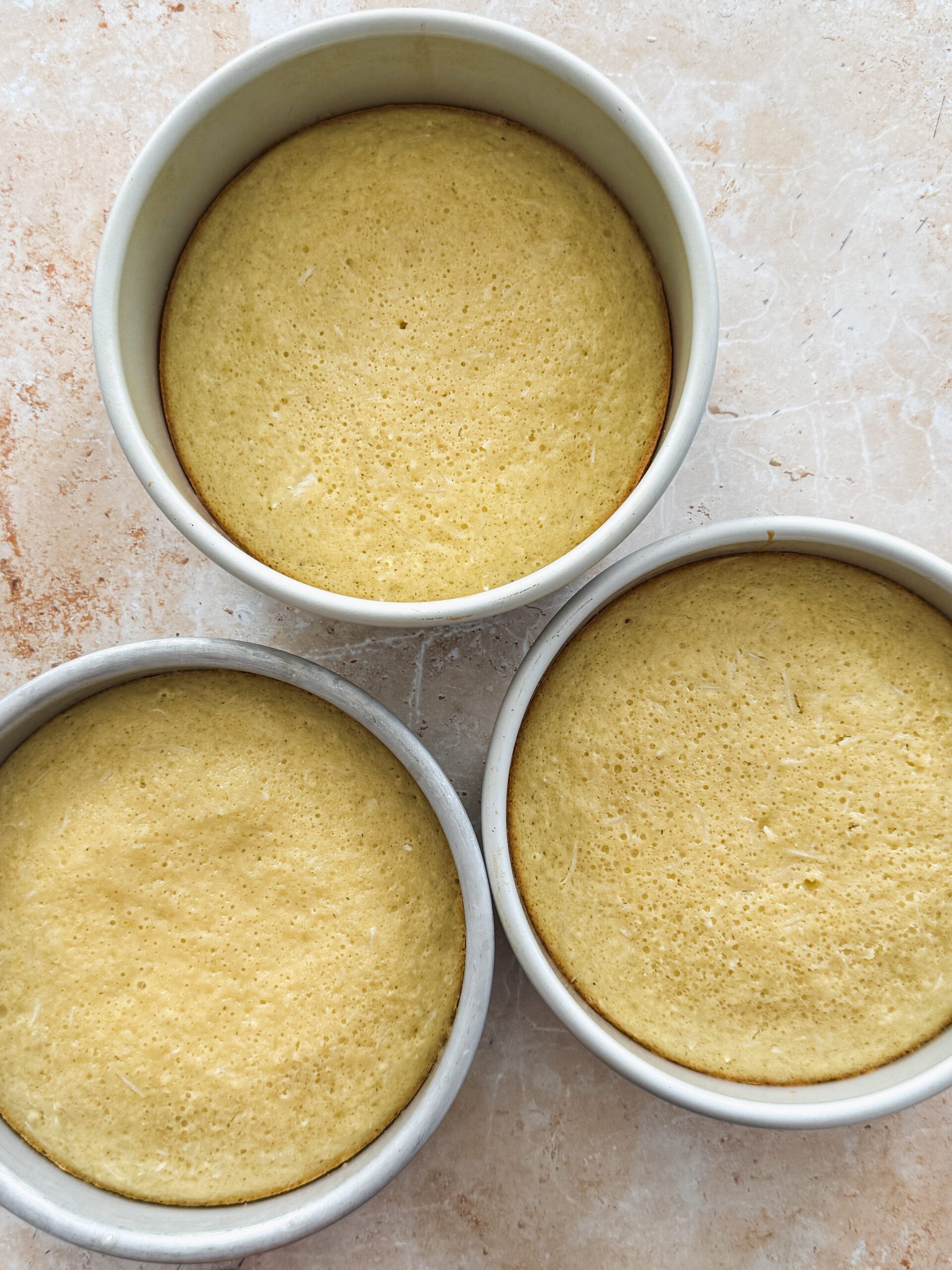 3 cake pans with baked coconut cake inside