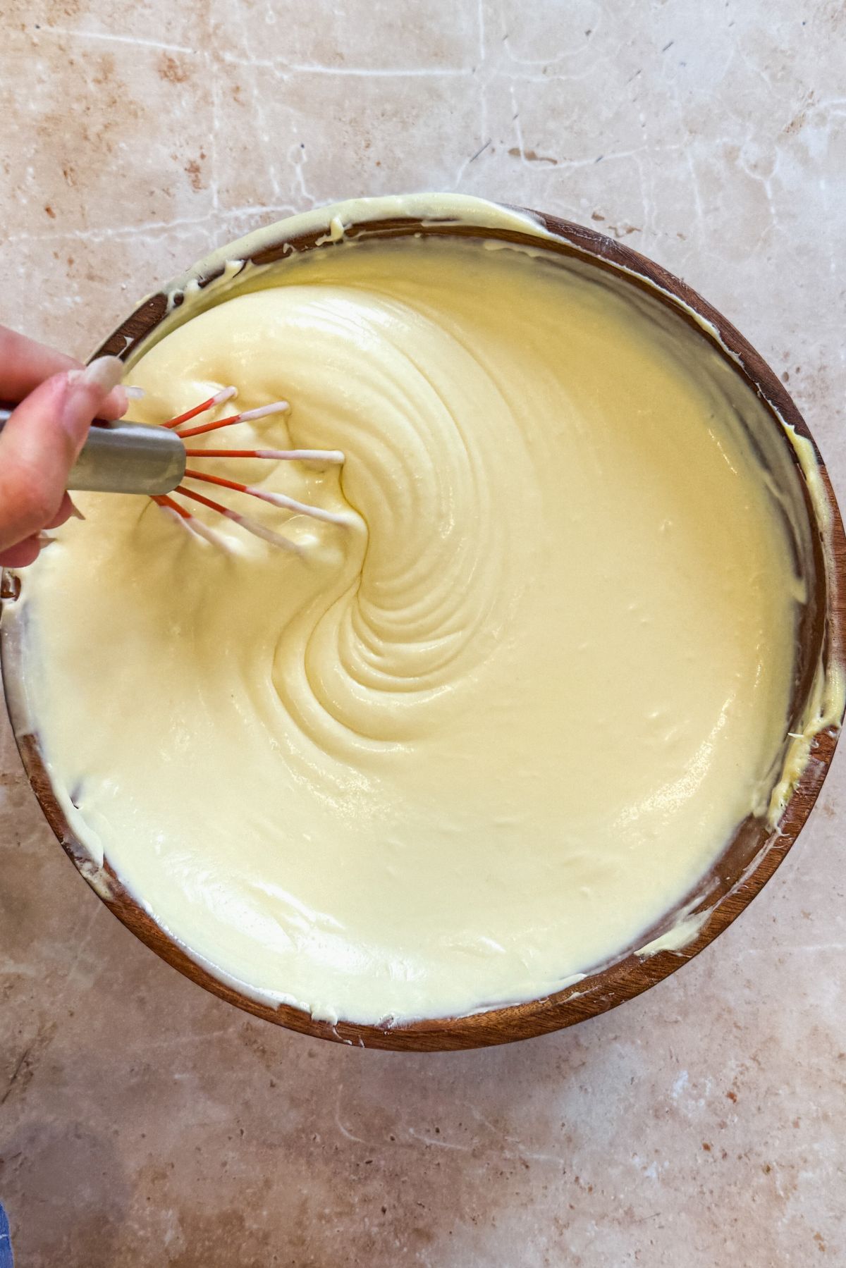 creamy mango cheesecake mixture in a wooden bowl