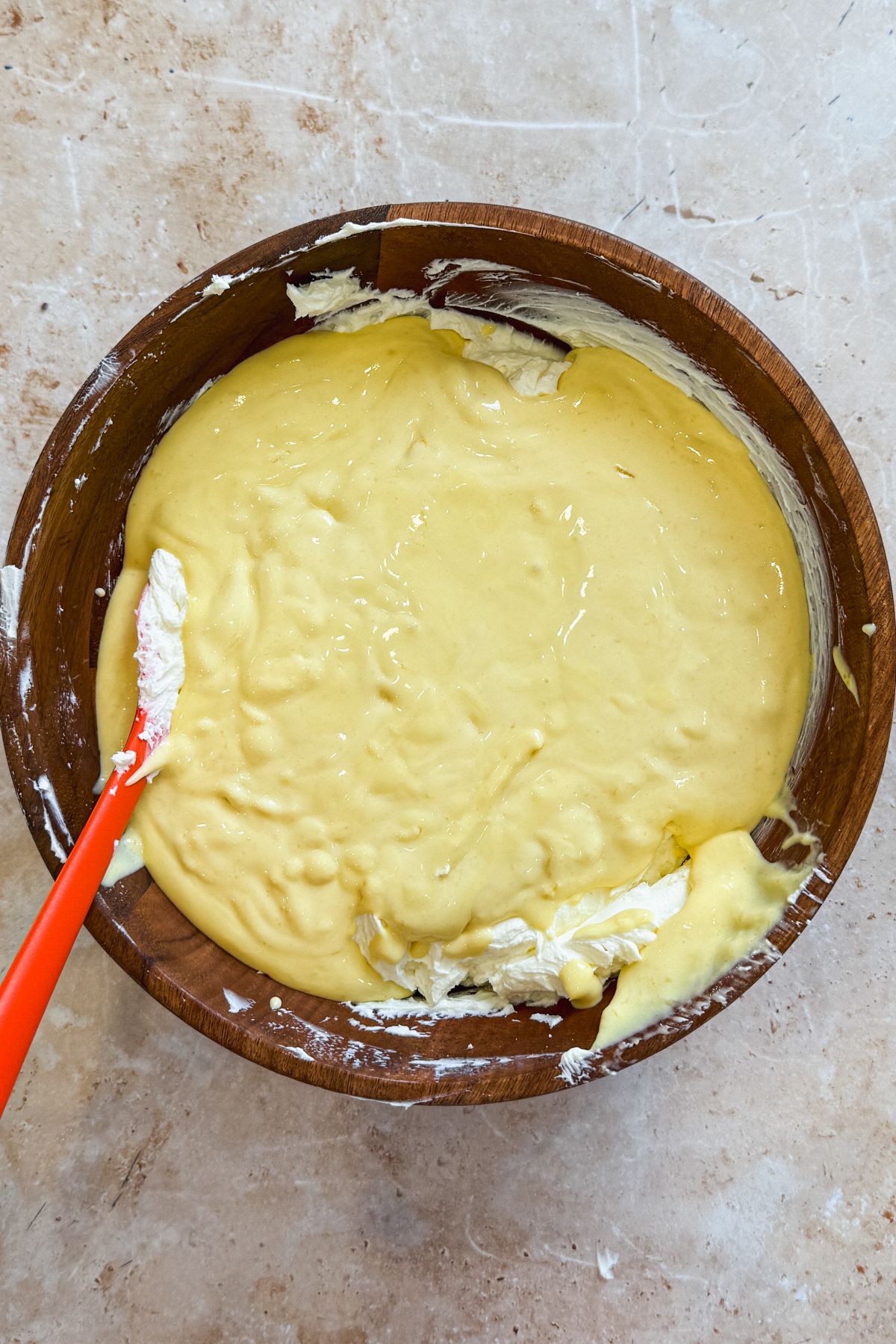 mango ice cream poured on top of cream cheese in a wooden bowl