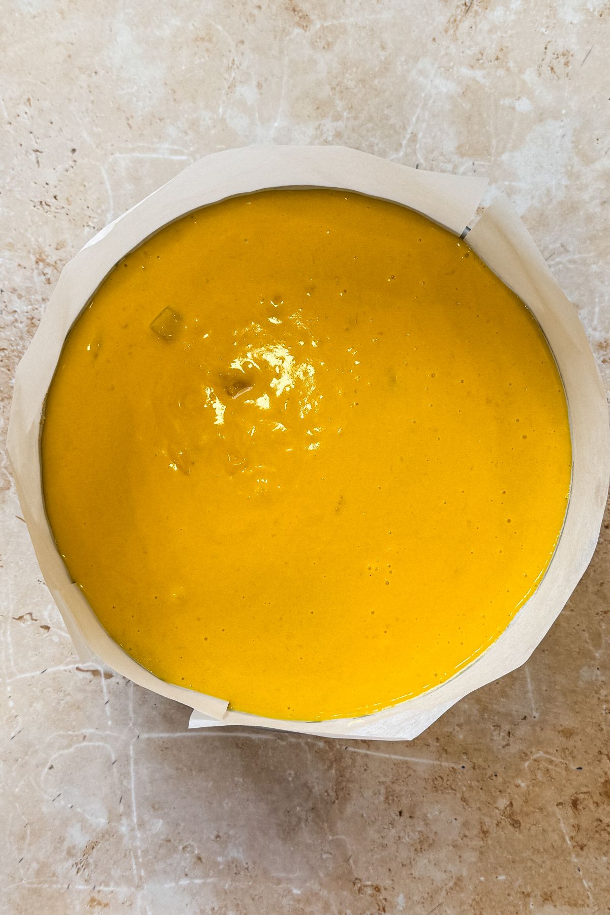 mango pulp layer poured on top of cheesecake layer in springform pan