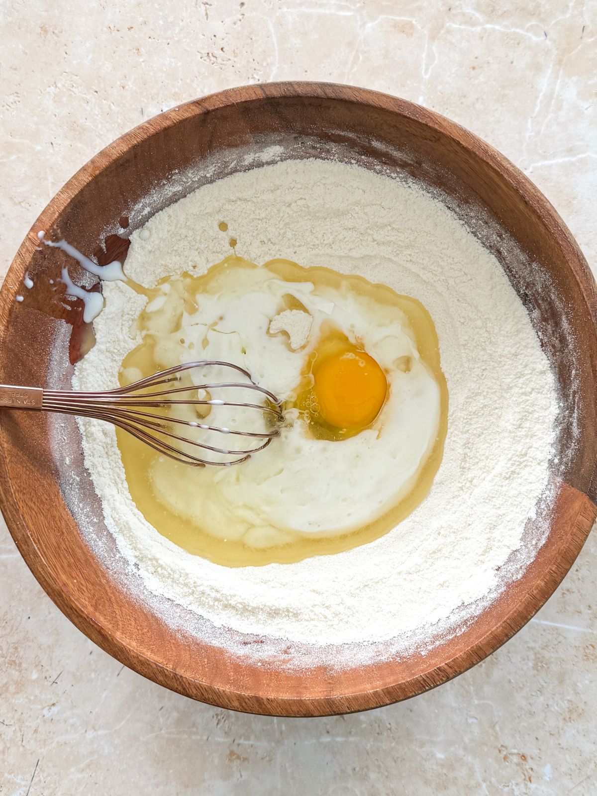 egg buttermilk and oil added to dry ingredients in a wooden bowl