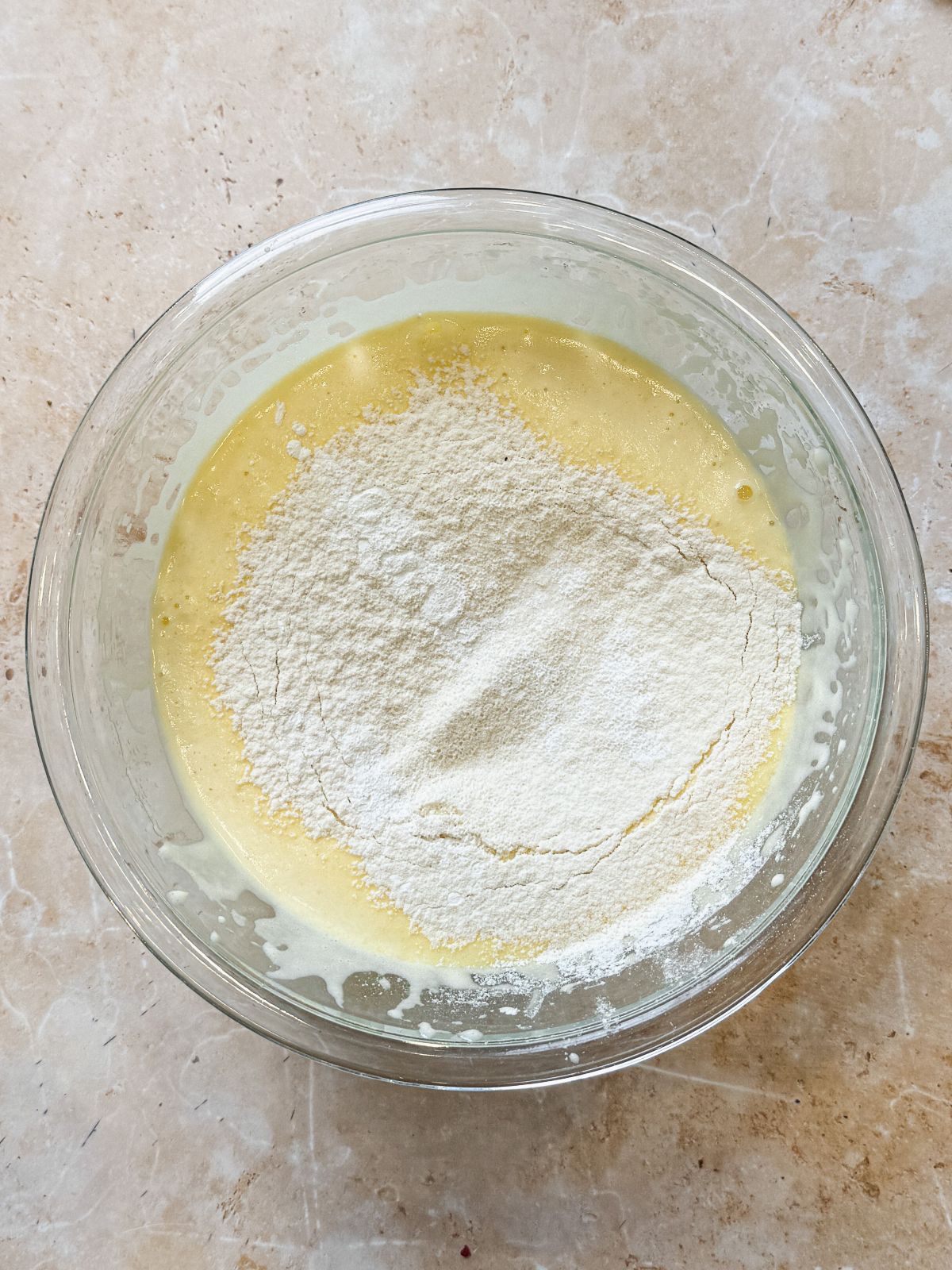dry ingredients sifted on top of whisked eggs and sugar in a glass bowl