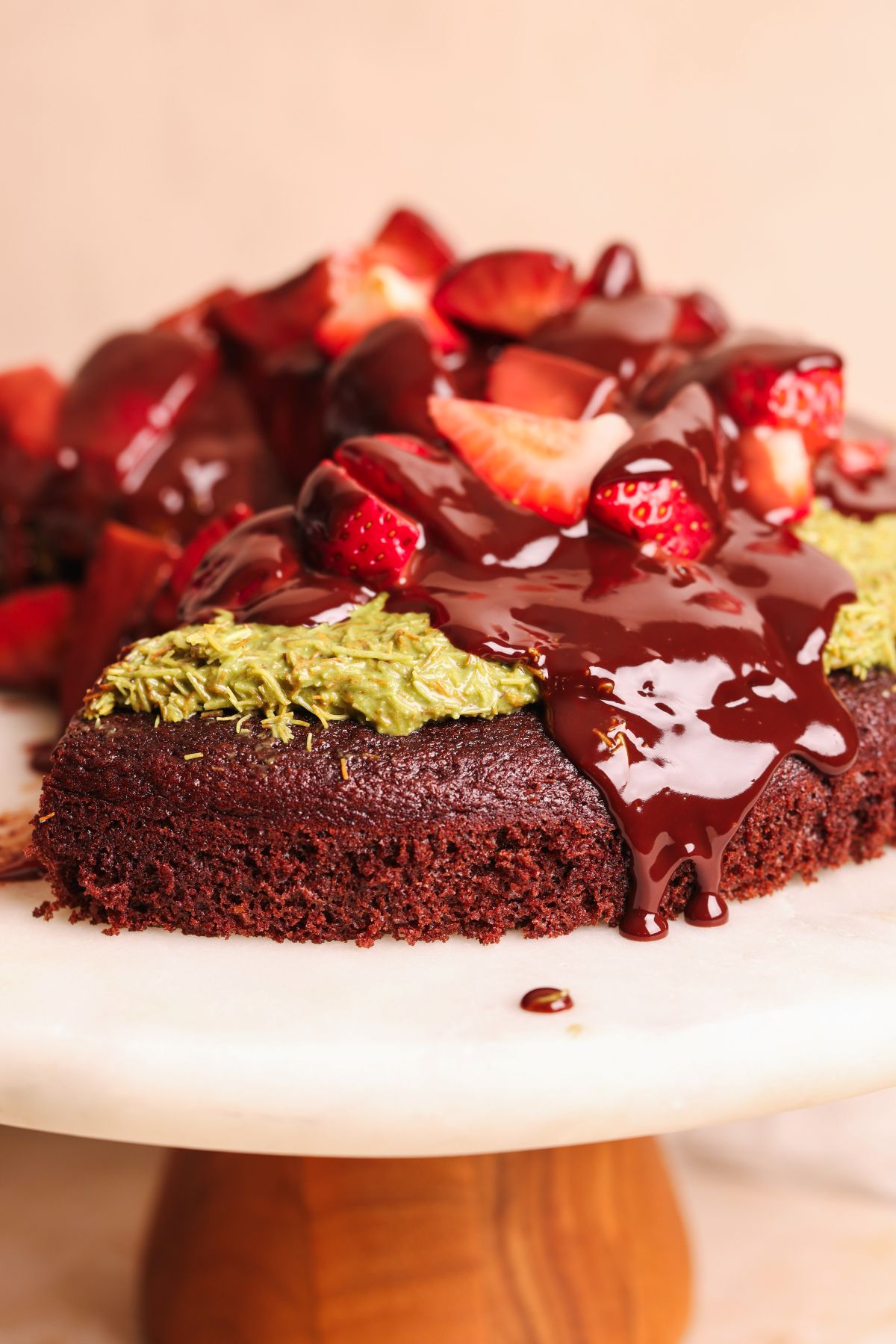 close up of dubai chocolate strawberry cake on a cake board with ganache dripping down the side