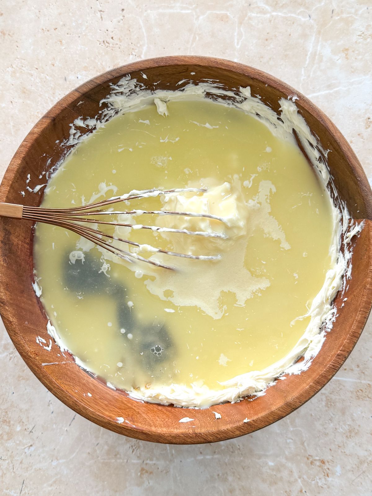 key lime juice added to cream cheese in a wooden bowl