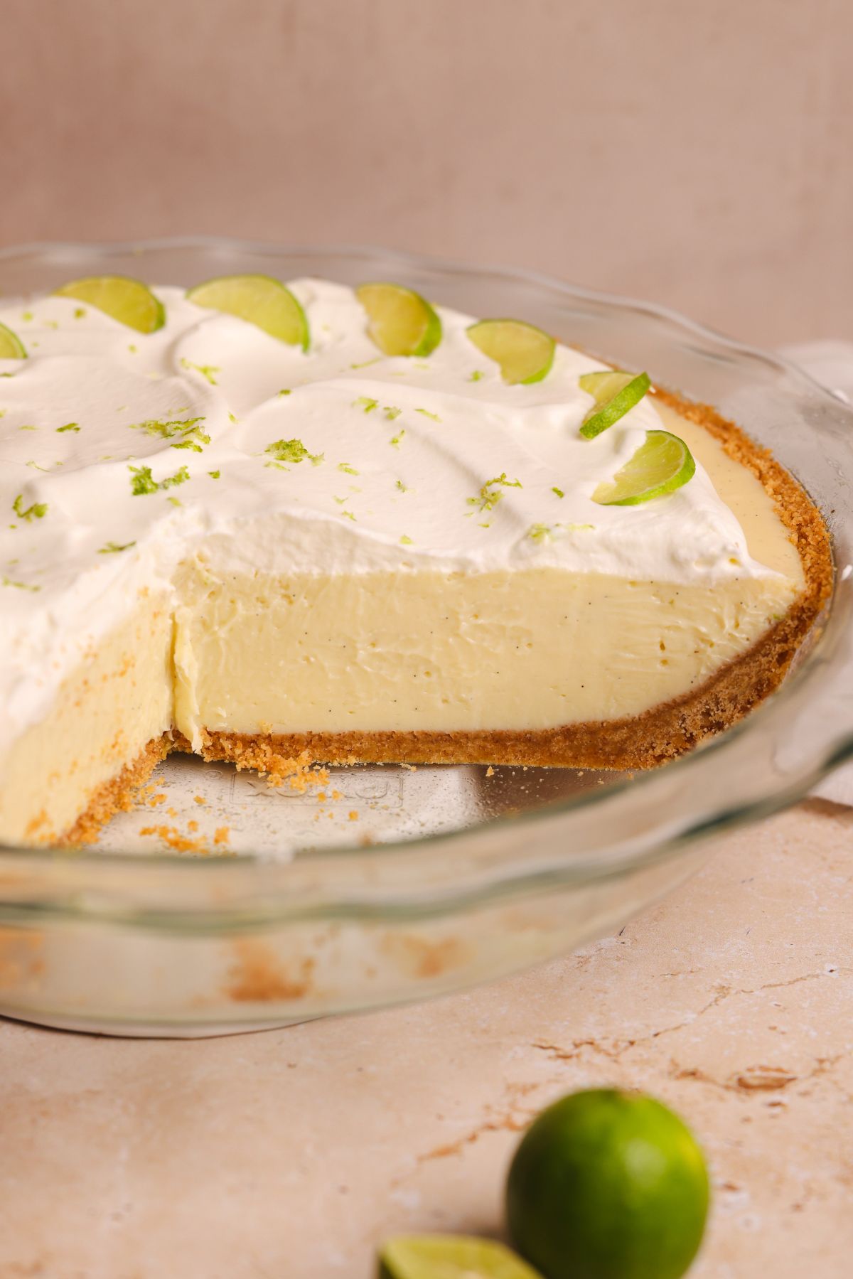 key lime pie with some slices removed to show the cross section of crispy crust and smooth creamy filling; pictured from the side