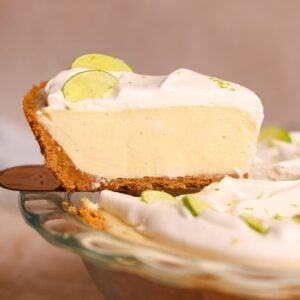 a spatula pulling a slice of key lime pie out of the pie. the pie has a crispy crust and a creamy smooth filling