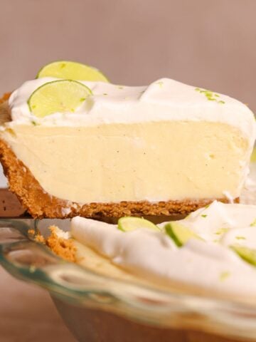 a spatula pulling a slice of key lime pie out of the pie. the pie has a crispy crust and a creamy smooth filling