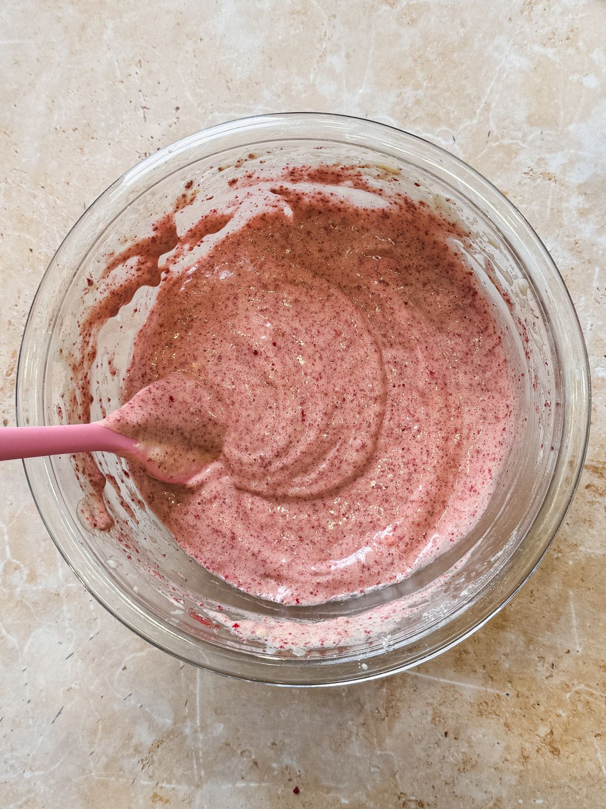 strawberry chiffon cake batter in a glass bowl with freeze dried strawberries folded in