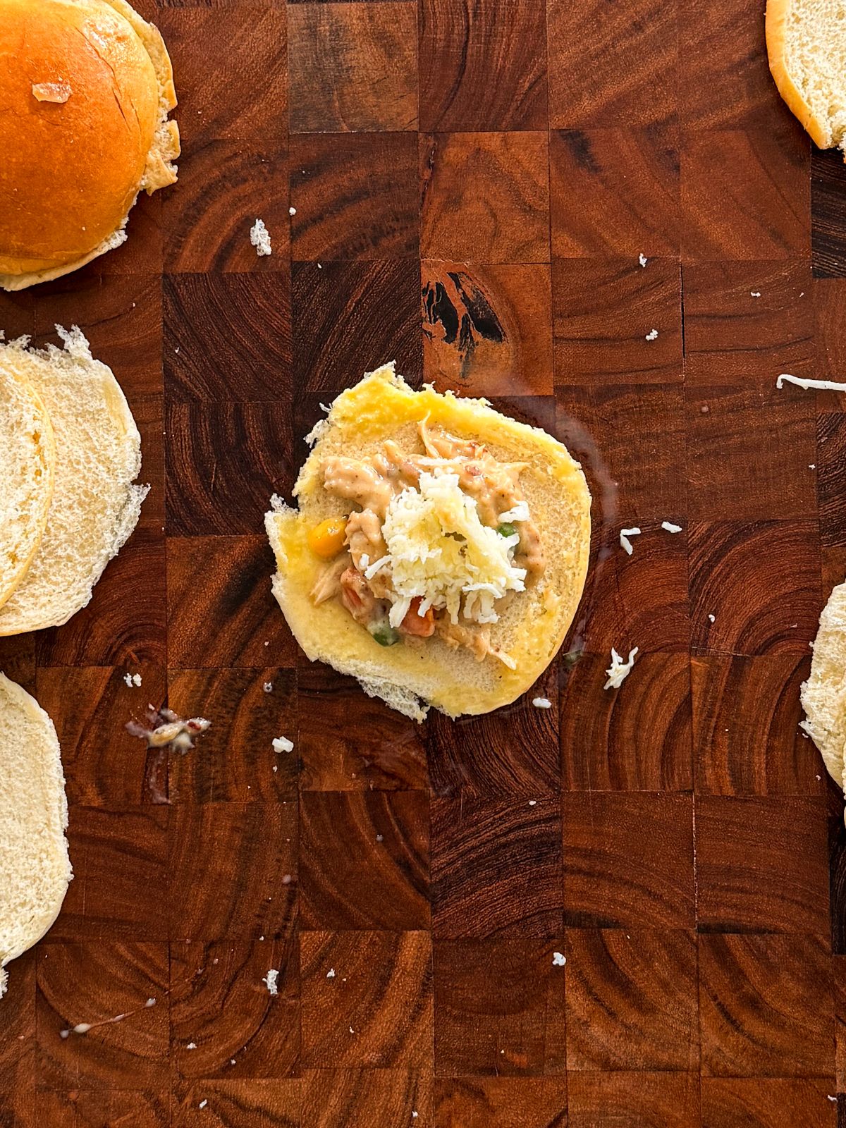 one flattened slider half with a scoop of pot pie filling and cheese on it