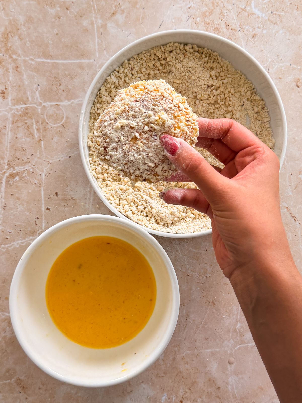hand holding a bread pocket coated in bread crumbs above a plate of crumbs